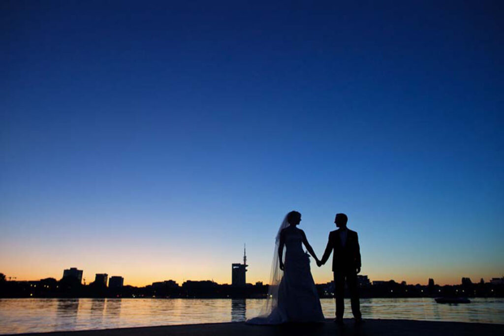 Ein Brautpaar zur blauen Stunde vor der Hamburger Skyline an der Alster